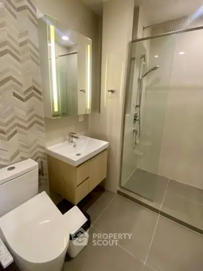Modern bathroom with glass shower and stylish vanity in contemporary apartment.