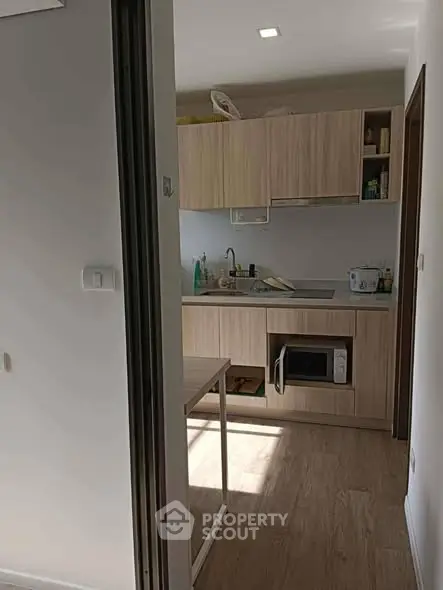 Modern compact kitchen with wooden cabinets and built-in appliances in cozy apartment.