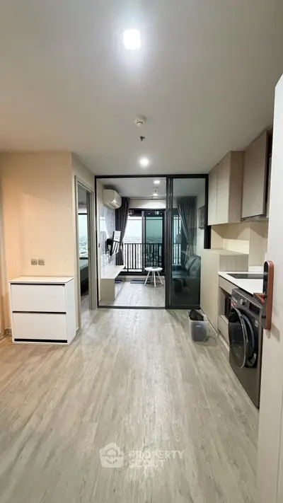 Modern open-plan kitchen with sleek appliances and balcony view in a stylish apartment.