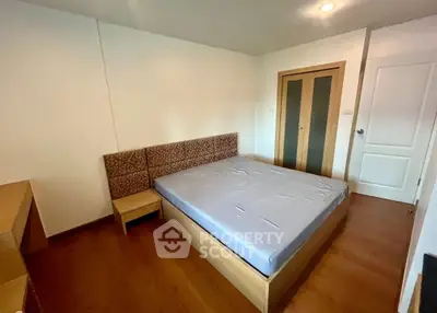 Spacious bedroom with modern wooden flooring and minimalist design, featuring a comfortable bed and ample closet space.