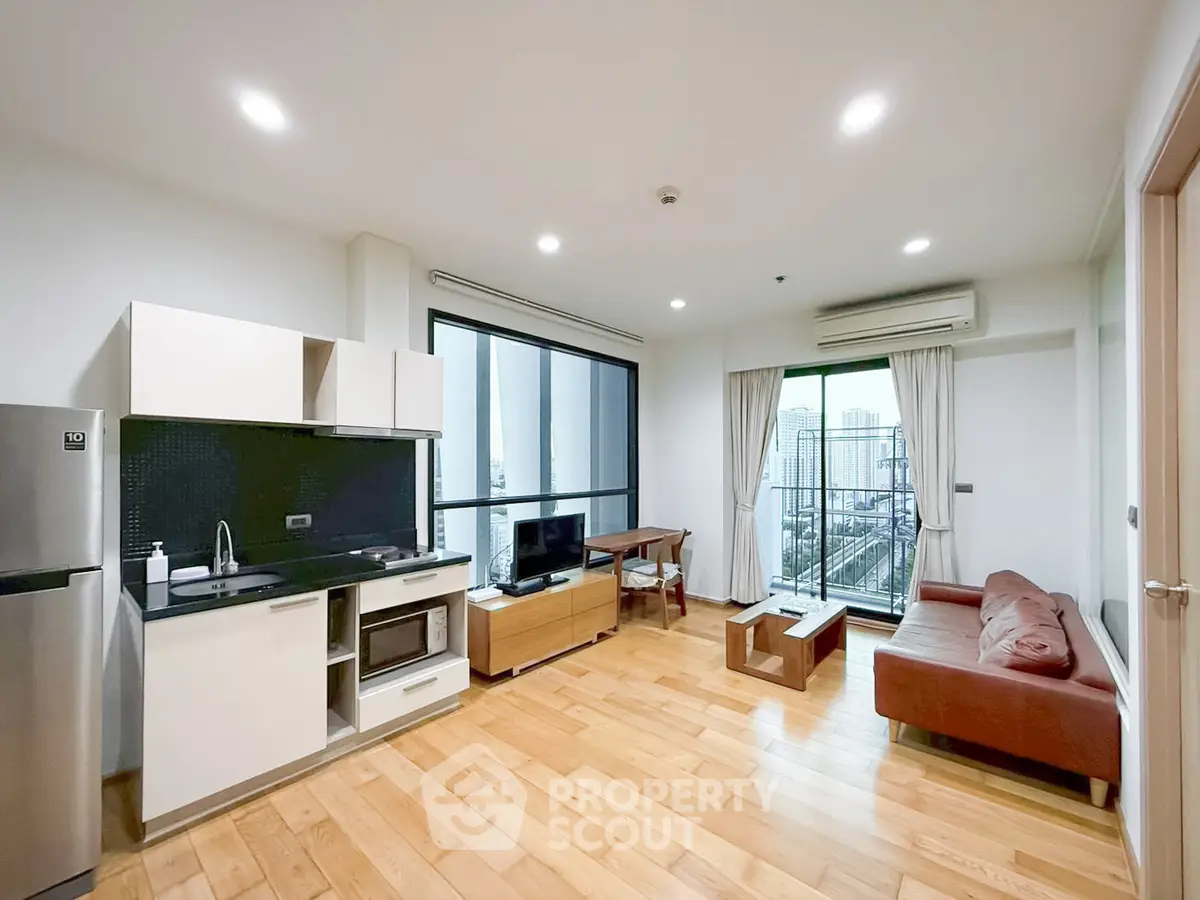 Modern living room with open kitchen and city view balcony in high-rise apartment.
