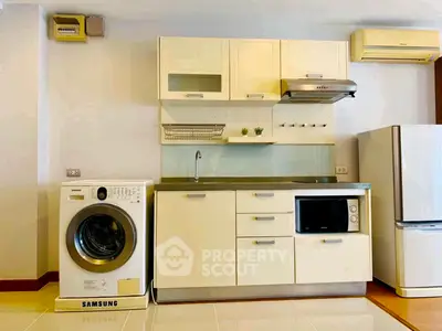 Modern kitchen with washing machine, fridge, and sleek cabinetry in a cozy apartment.