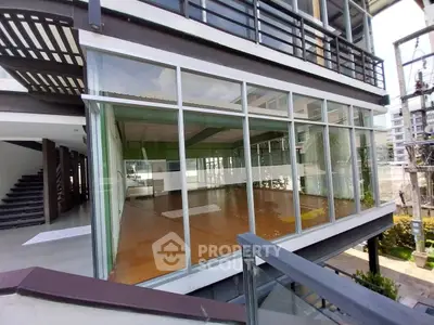 Modern glass-walled building with spacious interior and wooden flooring