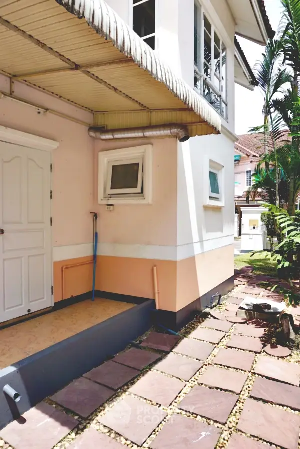Charming exterior view of a cozy house with a tiled pathway and lush greenery.