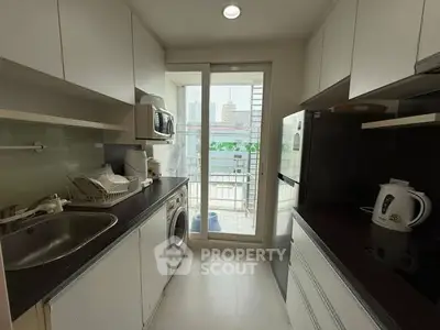 Modern kitchen with closed layout, featuring appliances and city view from window.
