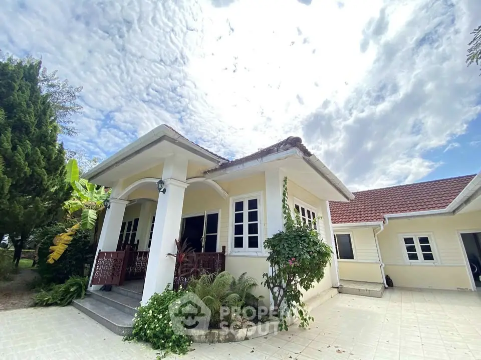 Charming single-story home with red-tiled roof and lush garden, perfect for serene living.