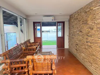 Charming sunlit room with rustic stone wall and bamboo seating, perfect for relaxation.
