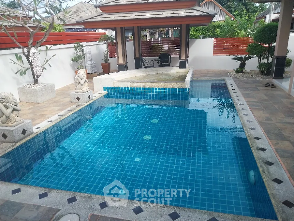 Luxurious outdoor pool with elegant stone statues and serene garden setting