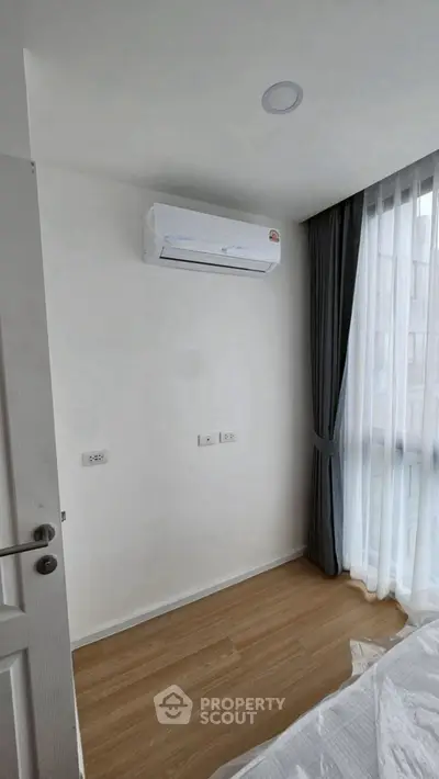 Modern bedroom with air conditioning and large window with curtains