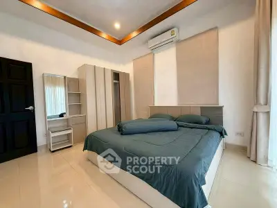 Spacious bedroom with modern furnishings and natural light, featuring a comfortable bed and stylish decor.