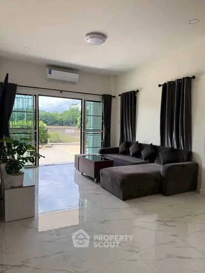 Spacious living room with modern sofa and large windows offering scenic views, perfect for relaxation.