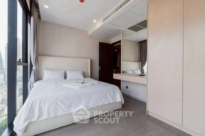 Modern bedroom with city view, featuring sleek design and ample natural light.