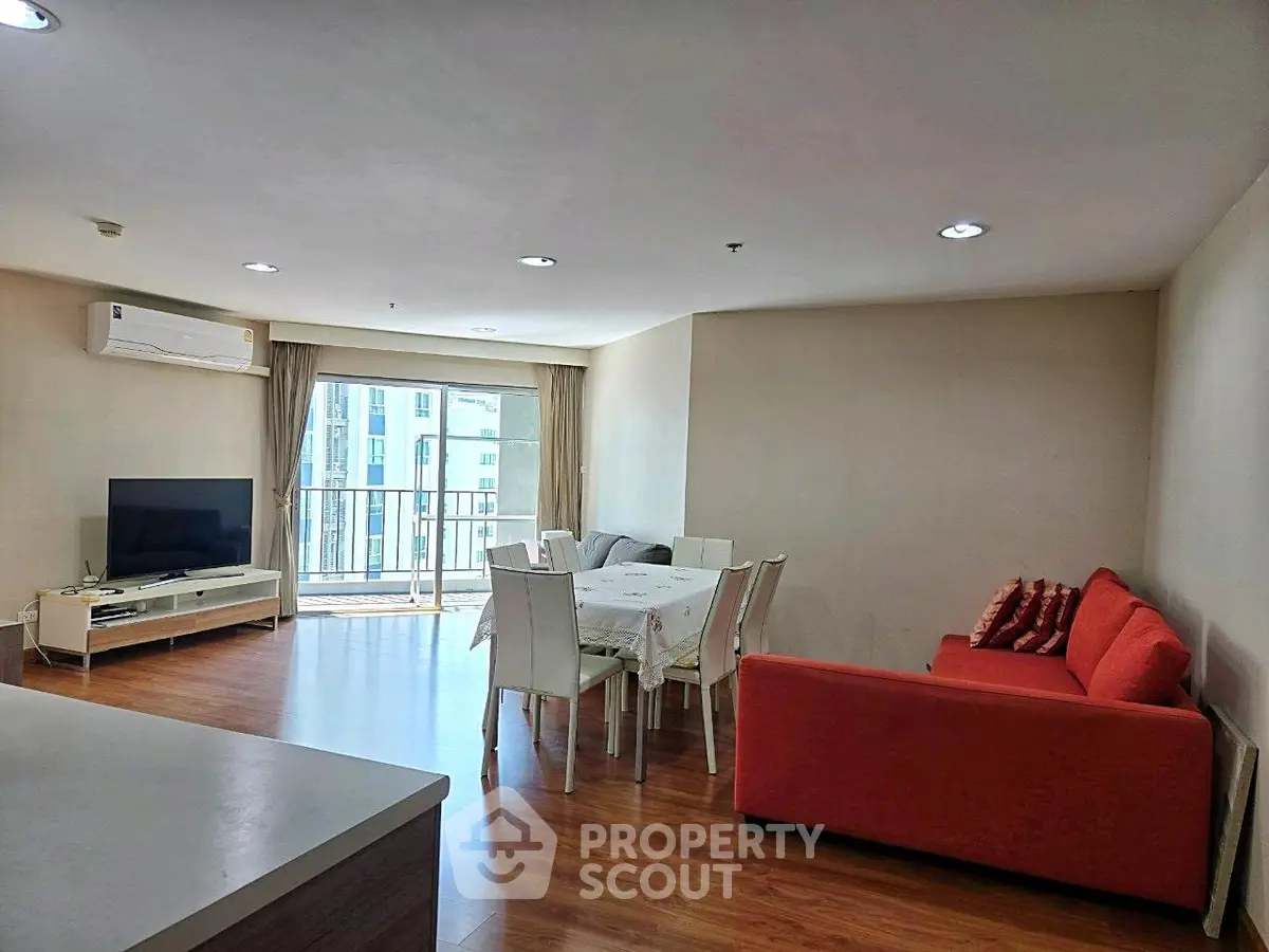 Spacious living room with modern furniture and balcony view in urban apartment.