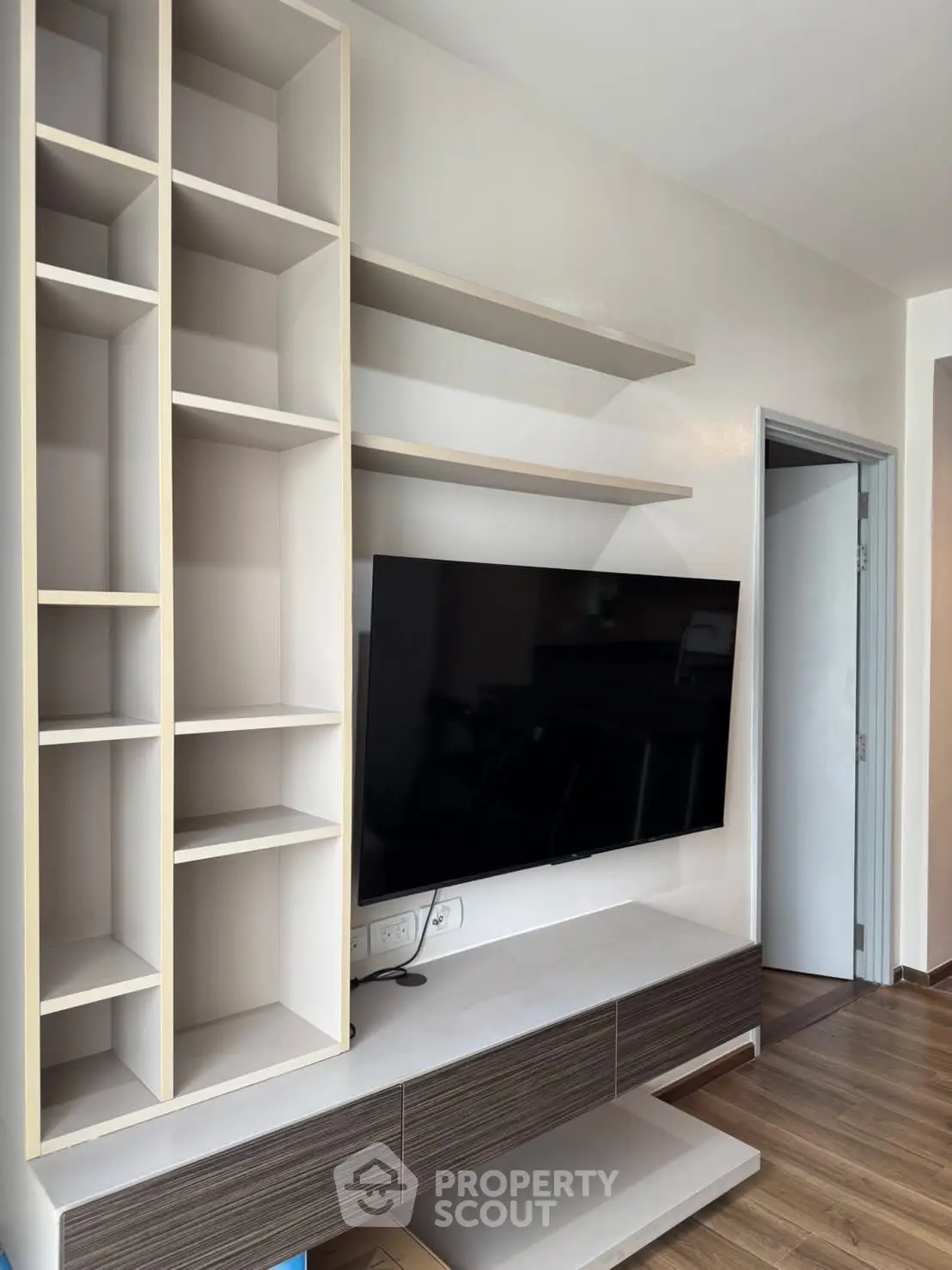 Modern living room with sleek TV unit and open shelving, perfect for stylish urban living.