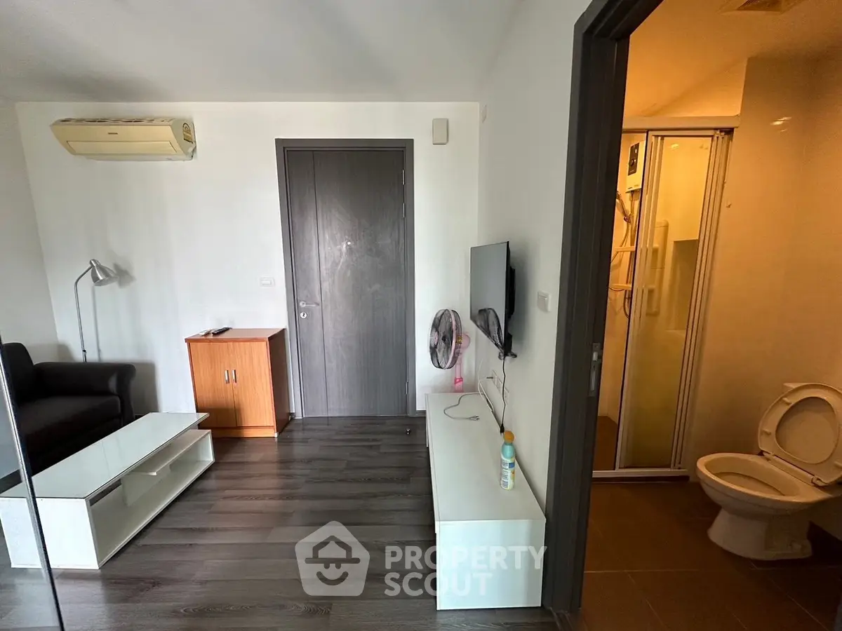 Modern apartment interior with sleek flooring and compact living area adjacent to bathroom.