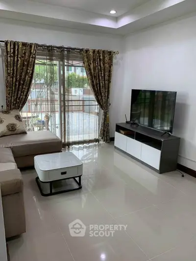 Spacious living room with modern decor and large TV, perfect for relaxation.