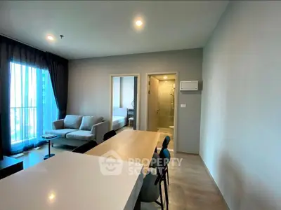 Modern open-plan living room with dining area and large windows in a stylish apartment.