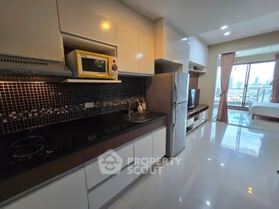 Modern kitchen with sleek cabinetry and open layout leading to a bright living area with city view.