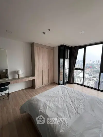Spacious bedroom with city view, featuring modern decor and large windows for natural light.