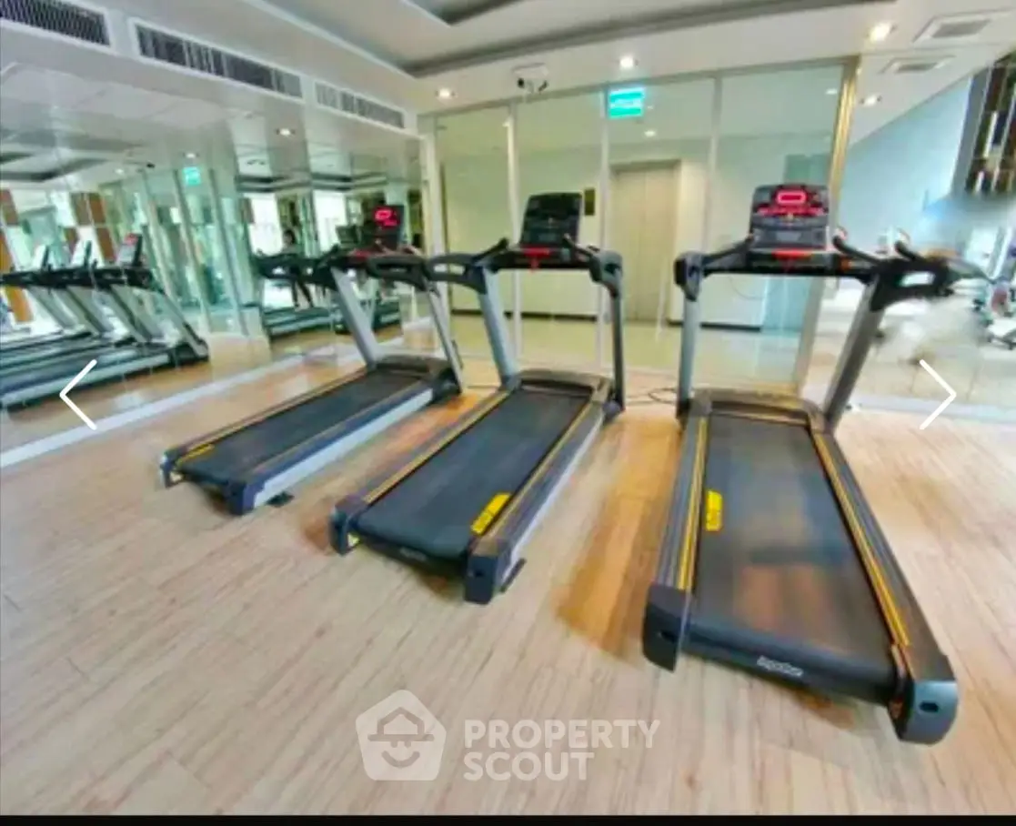 Modern gym with multiple treadmills and mirrored walls in luxury real estate property.