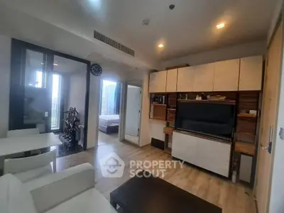 Modern living room with open layout and stylish furniture, featuring a glimpse of a cozy bedroom.