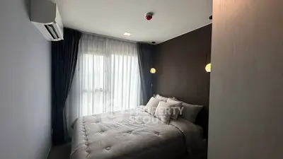 Modern bedroom with cozy bedding and natural light from large window.
