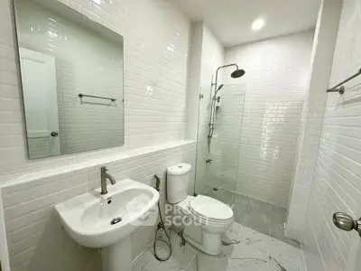 Modern bathroom with sleek white tiles and glass shower enclosure