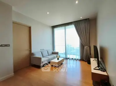 Modern living room with sleek furniture and large window offering natural light.