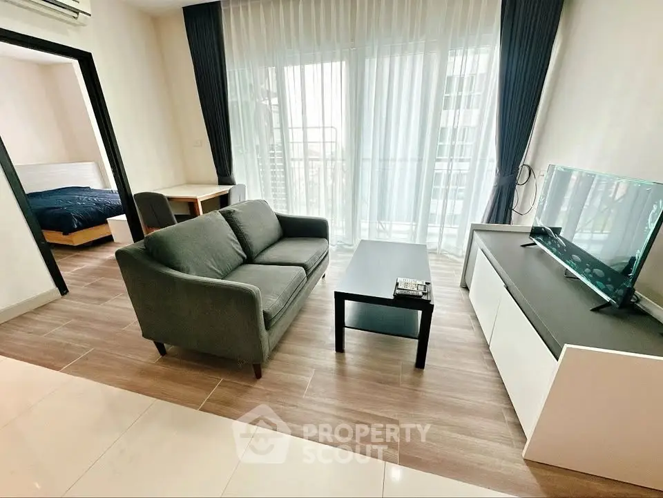 Modern living room with sleek furniture and natural light, adjacent to a cozy bedroom.