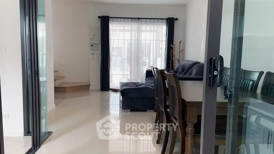 Spacious living room with elegant dining area and modern furniture, featuring large windows for natural light.