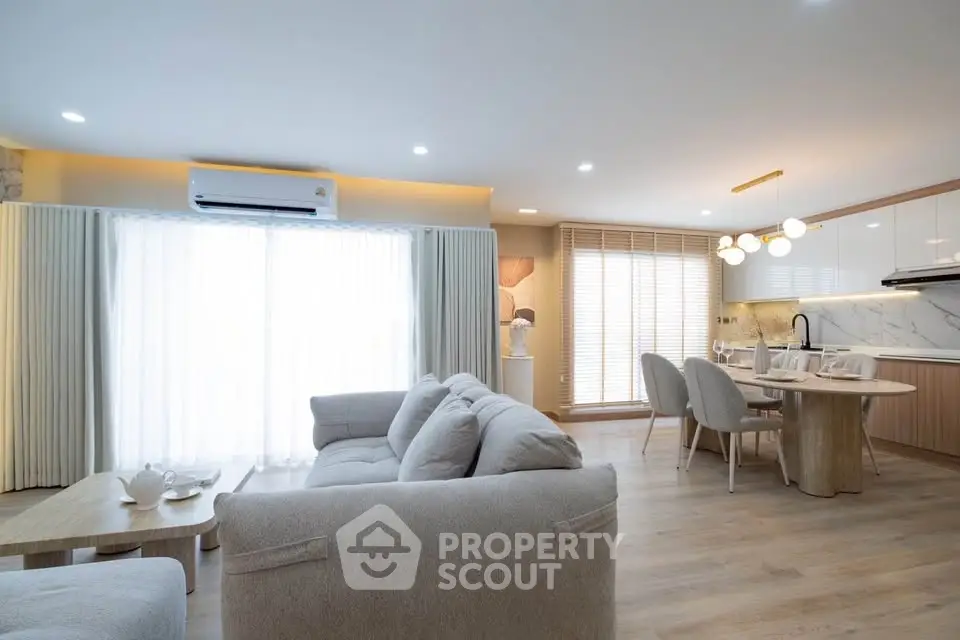Spacious modern living room with open kitchen and elegant dining area, featuring cozy seating and natural light.
