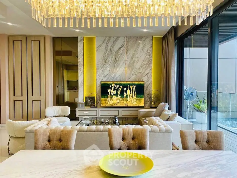 Luxurious living room with elegant chandelier and modern decor, featuring a spacious open layout and balcony view.