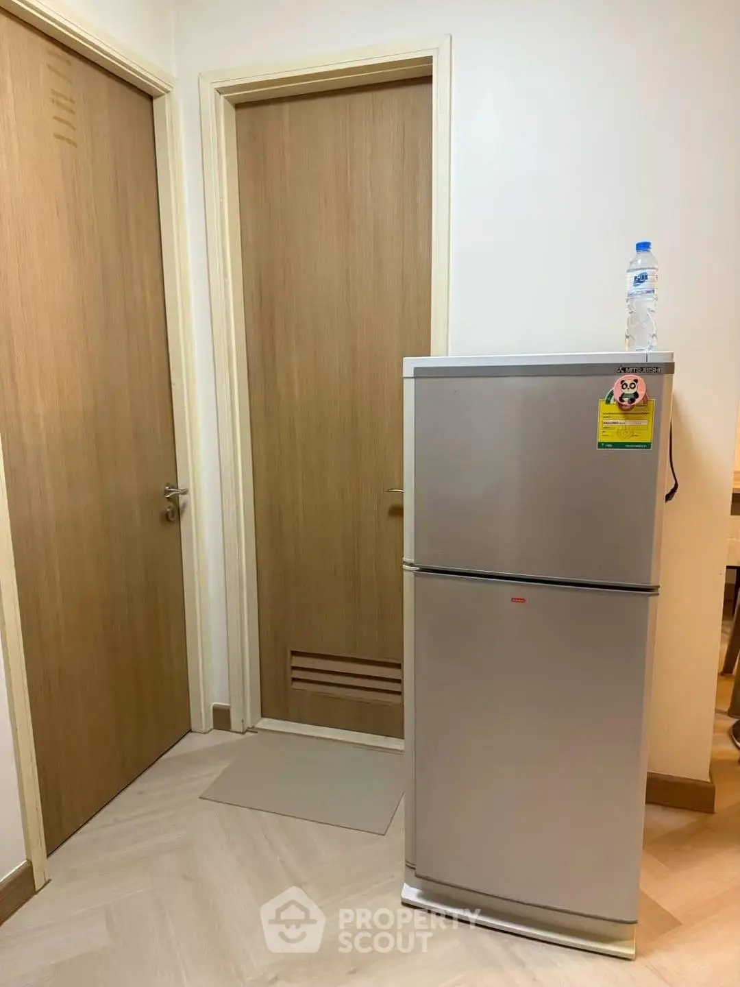 Compact kitchen area with modern fridge and wooden doors
