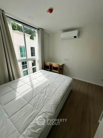 Bright bedroom with large window and modern air conditioning unit, perfect for comfort and relaxation.