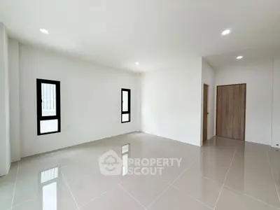 Spacious empty room with modern tile flooring and natural light from windows.