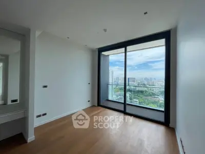 Spacious room with stunning city view and large glass doors leading to balcony.
