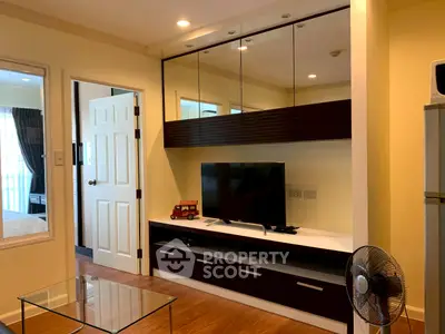 Modern living room with sleek TV unit and glass coffee table in cozy apartment.