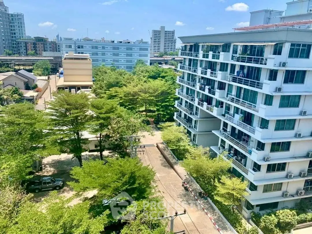 Stunning aerial view of modern apartment complex surrounded by lush greenery in urban setting.