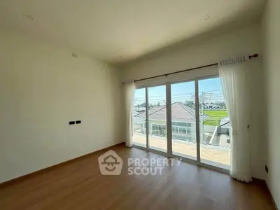 Spacious bedroom with large windows and balcony offering a scenic view, perfect for natural light lovers.