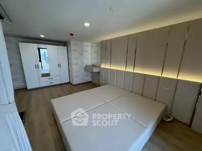 Modern minimalist bedroom with sleek design and city view, featuring built-in wardrobe and ambient lighting.
