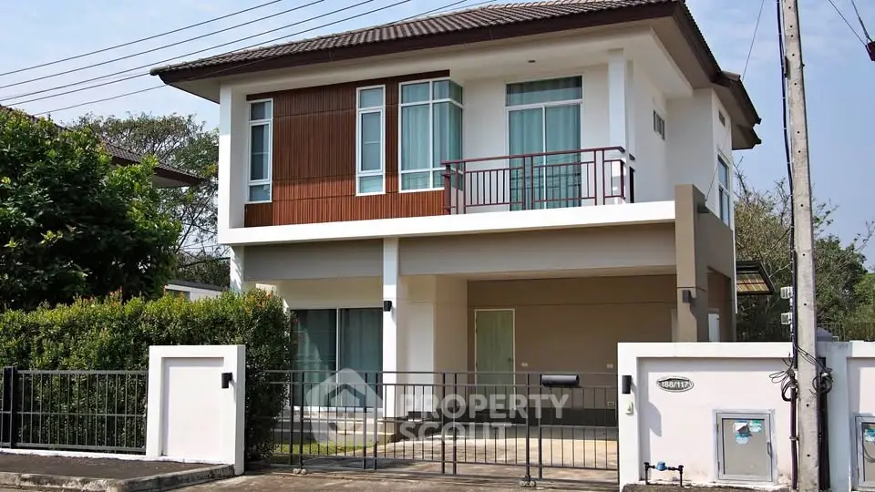 Modern two-story house with a sleek design and gated driveway in a suburban neighborhood.