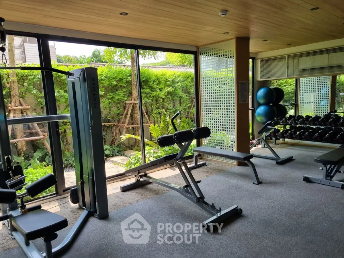 Spacious gym with modern equipment and garden view in luxury real estate property.