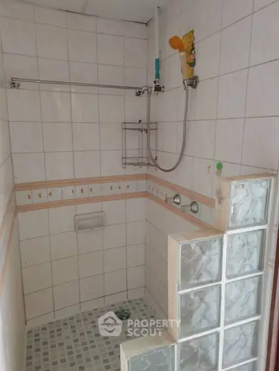 Cozy bathroom with tiled shower area and glass block partition, perfect for modern living.