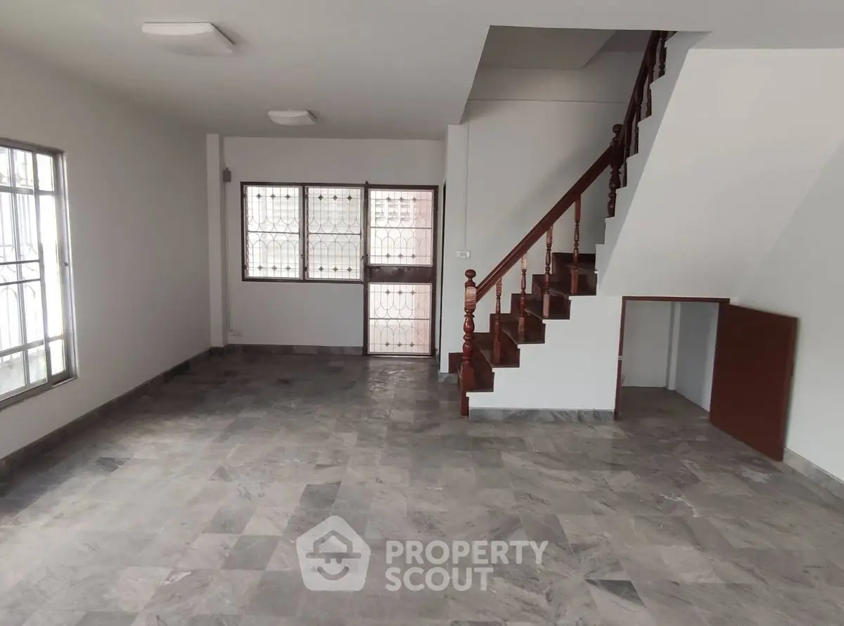 Spacious living room with marble flooring and elegant staircase in modern home.