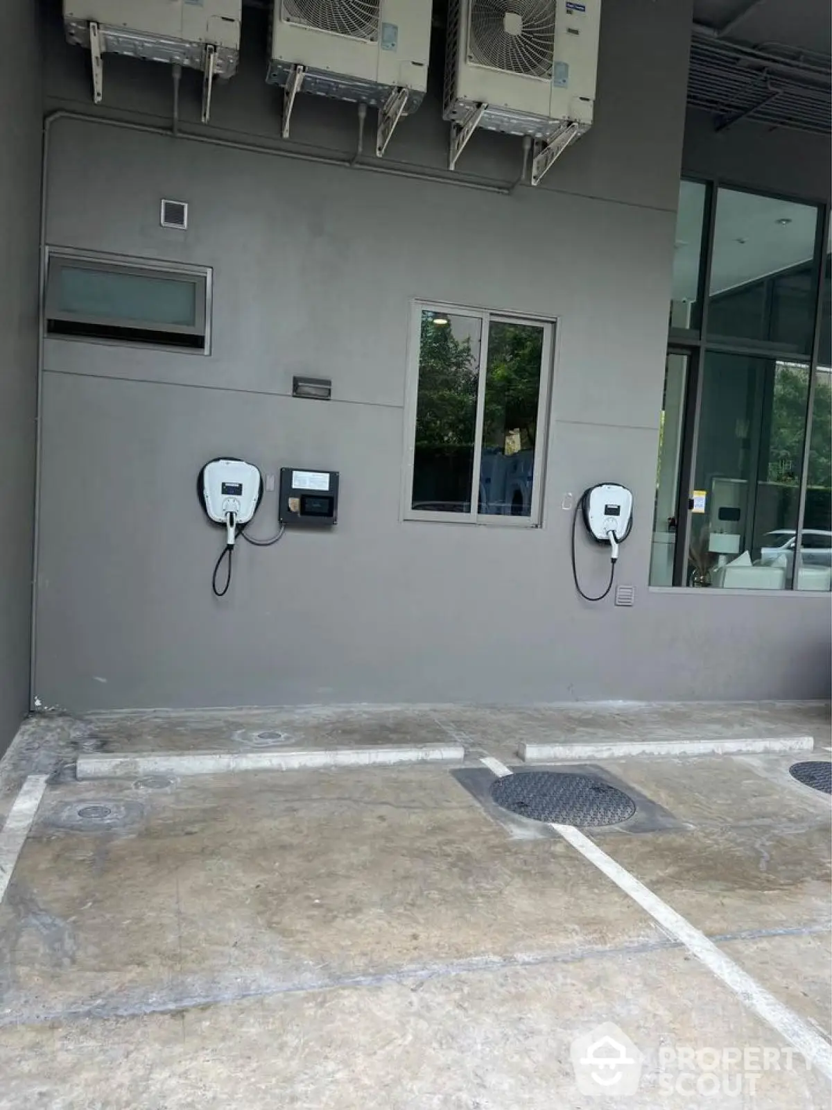 Modern building exterior with electric vehicle charging stations and large windows.