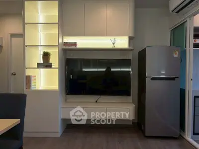 Modern living room with sleek TV setup and stainless steel fridge, perfect for contemporary living.