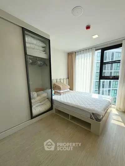 Modern bedroom with large windows and built-in storage in a high-rise apartment.