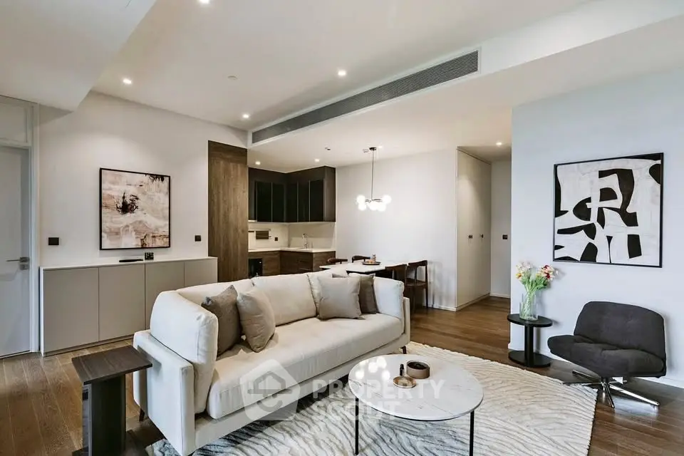 Modern living room with stylish decor and open kitchen layout, featuring elegant furniture and contemporary art.