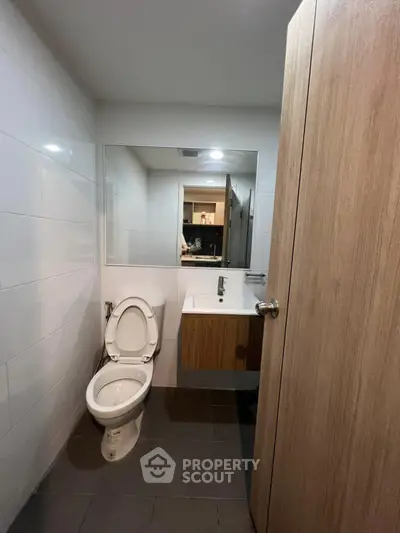 Modern bathroom with sleek fixtures and large mirror in contemporary apartment.