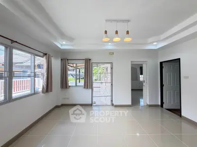 Spacious living room with modern lighting and large windows in a bright home.